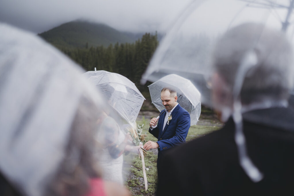 Canmore couple using umbrellas they brought as a backup plan at their mountain elopement. 