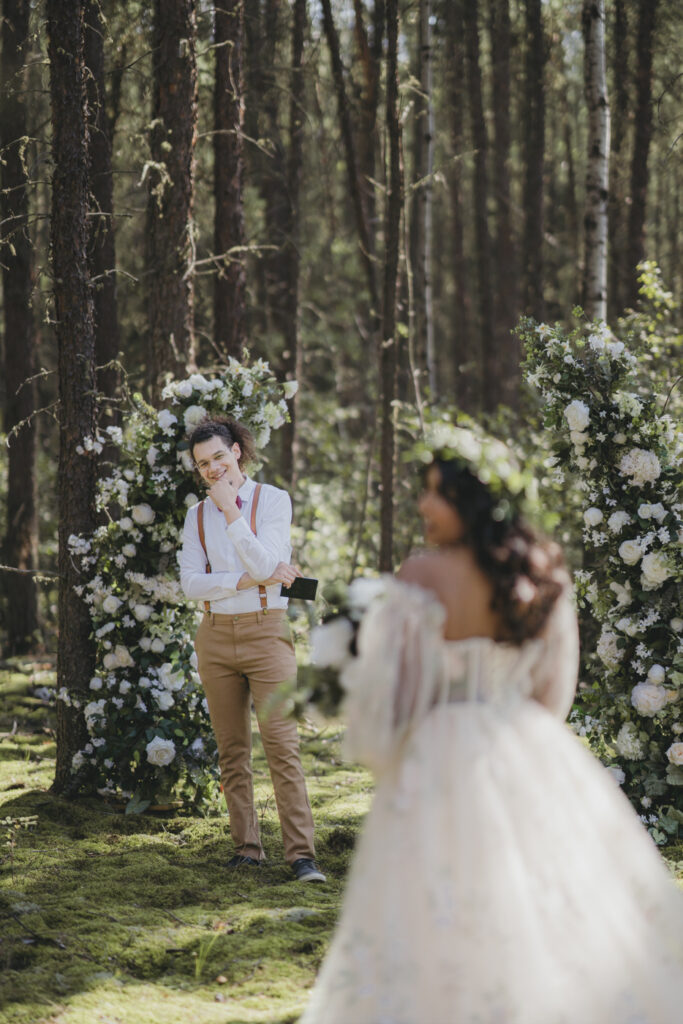 A boho bride walking down the isle toward her groom, getting married in the forest.