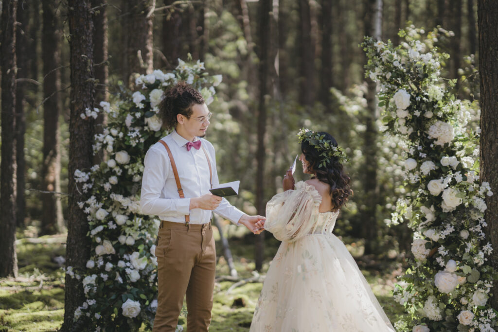 A boho bride and groom saying their vows in the forest.