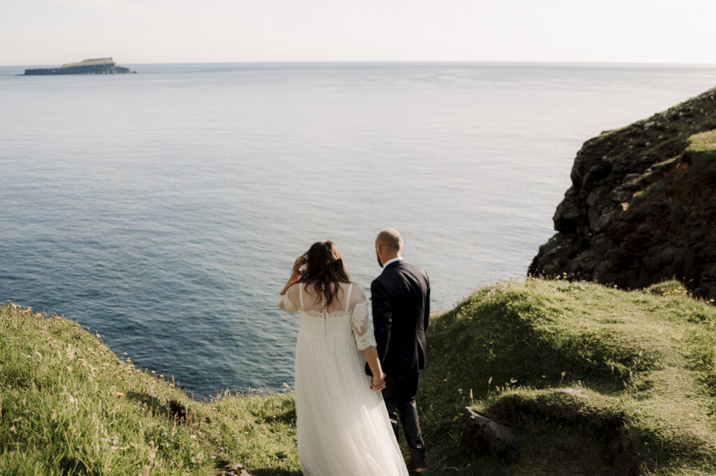 Faroe Islands Elopement couple overlooking a beautiful waterfall at the edge of a cliff. 