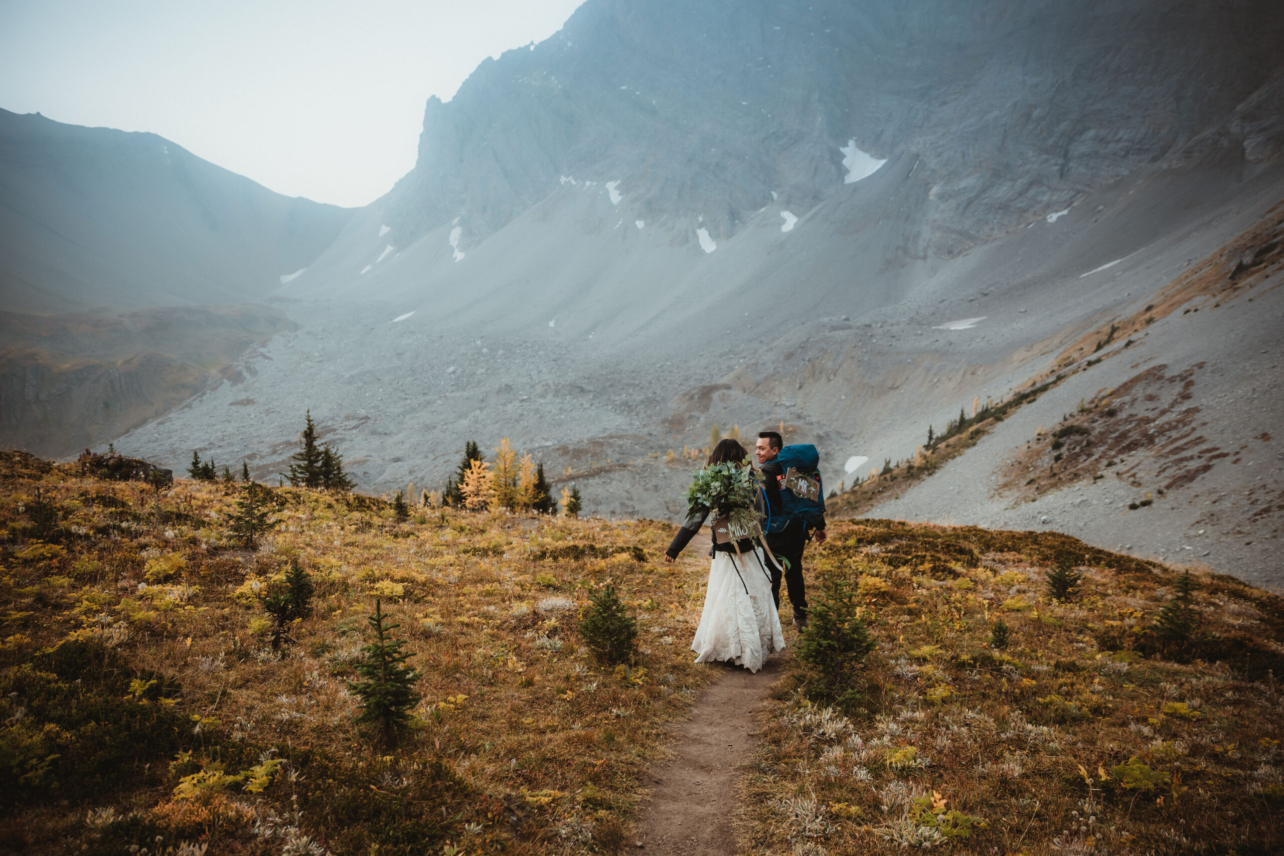 Elopement couple walking along the larches on a hiking path in Kananakis.