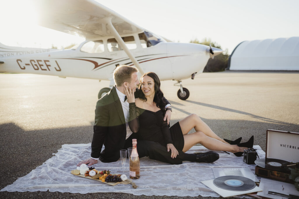 Couple celebrating their engagement at Edmonton Flight Flub in front of an airplane. 