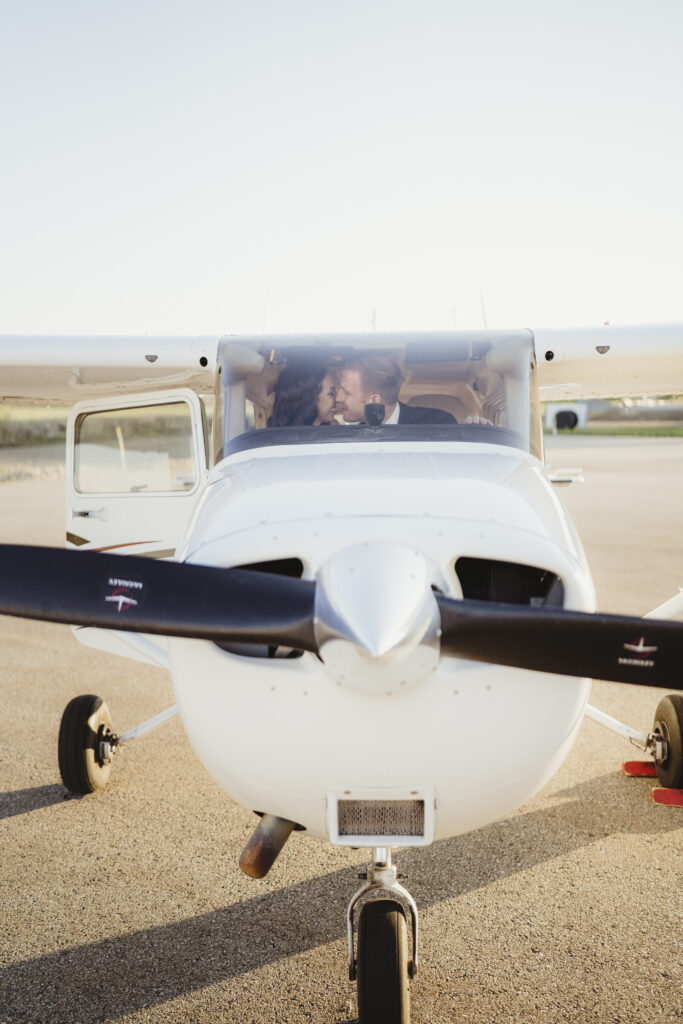 Couple kissing in an airplane during their couple photos at the Edmonton flight club. 